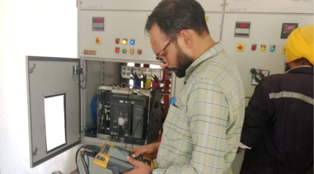 Energy audit expert performing electrical inspection in industrial control panel