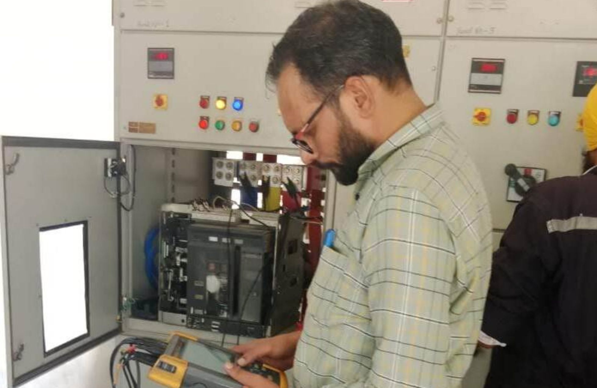 Energy audit expert performing electrical inspection in industrial control panel