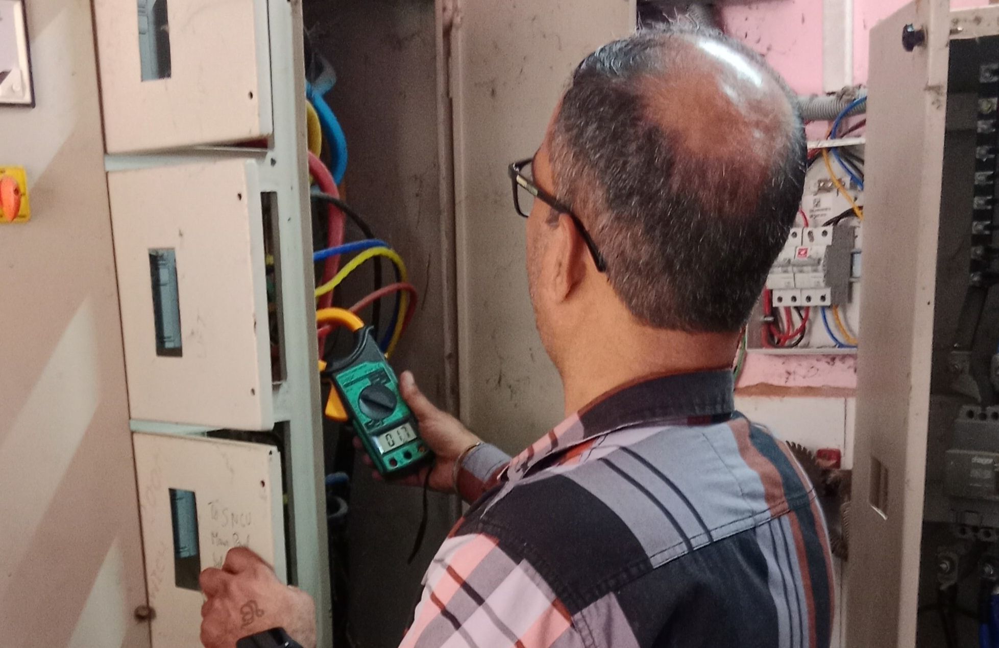 Electrical safety audit expert checking industrial control panel and cables for hazards